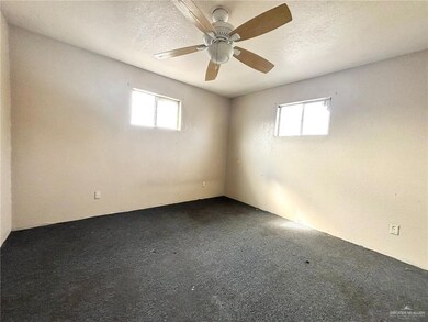Unfurnished room featuring ceiling fan, carpet floors, and a textured ceiling