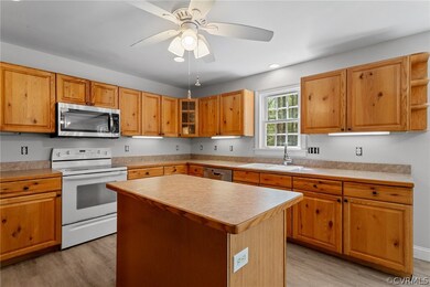 Kitchen with a center island, appliances with stainless steel finishes, sink, light hardwood / wood-style floors, and ceiling fan