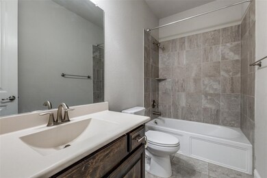 Full bathroom featuring  shower combination, vanity, a textured wall, and light tile patterned flooring