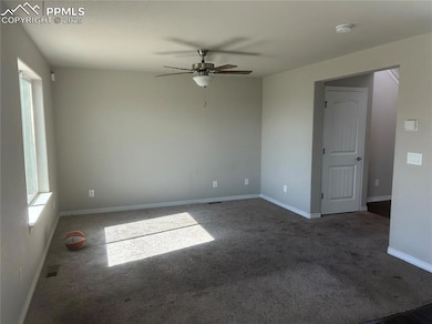 Empty room featuring ceiling fan, carpet floors, and a smoke detector