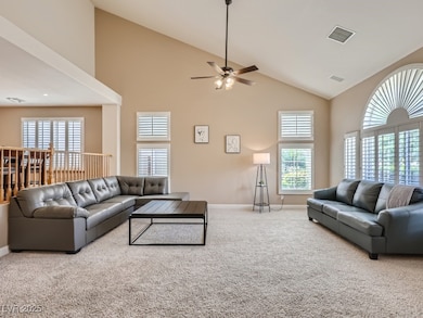 Family room with high vaulted ceiling, light tile patterned floors, light carpet, shutters, and a ceiling fan with light