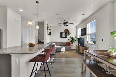 Kitchen featuring light wood finished floors, a ceiling fan, a kitchen island, stone counters, and a textured ceiling
