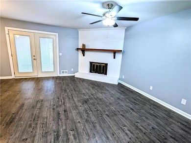 Unfurnished living room featuring dark wood-type flooring, a fireplace, and french doors
