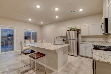 Kitchen with light stone countertops, a kitchen breakfast bar, visible vents, a sink, and stainless steel appliances