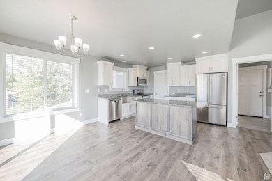 Kitchen with stainless steel appliances, light stone countertops, recessed lighting, decorative light fixtures, and light wood-type flooring