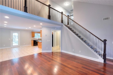 Unfurnished living room with a high ceiling, recessed lighting, light wood-type flooring, and stairs
