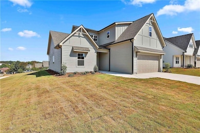 Modern farmhouse style home featuring a front yard, roof with shingles, driveway, a garage, and board and batten siding