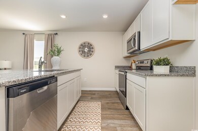 Kitchen with stainless steel appliances, light wood-style flooring, white cabinetry, and recessed lighting