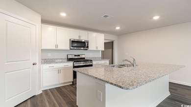 Kitchen with white cabinetry, sink, an island with sink, and appliances with stainless steel finishes