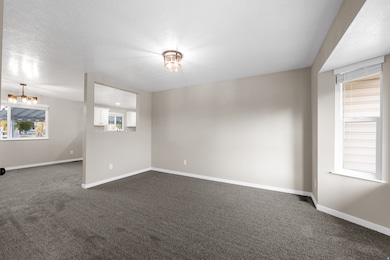 Empty room featuring dark carpet and a textured ceiling