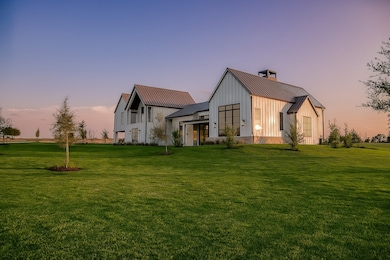 Under a painted Texas sky, the home glows in soft gold—clean lines, gabled symmetry, & the quiet authority of a Brickmoon design meant to endure.