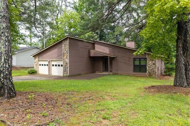 View of front of property featuring stone siding, a chimney, a garage, a front yard, and driveway