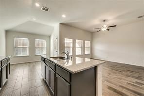 Kitchen with a healthy amount of sunlight, light hardwood / wood-style floors, and an island with sink