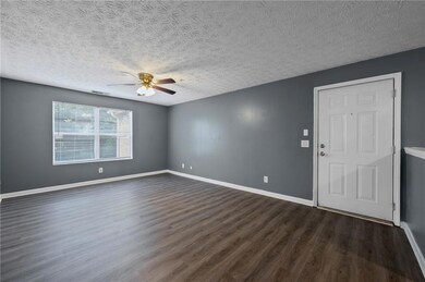 Spare room with ceiling fan, dark wood-style floors, and a textured ceiling