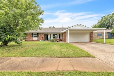 Single story home featuring a garage, concrete driveway plus covered parking, a front lawn, and brick siding