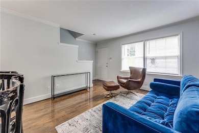 Living area with crown molding, wood finished floors, and baseboards