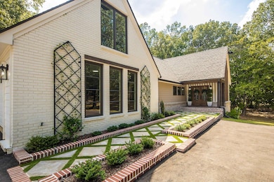 View of front facade featuring brick siding, roof with shingles, and a patio