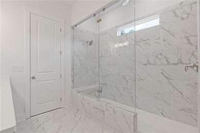 Bathroom with a marble finish shower, marble look tile flooring, and vanity