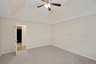 Empty room with carpet floors, ceiling fan, baseboards, and a raised ceiling
