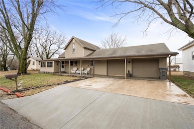 View of front of property with a garage, concrete driveway, a porch, and a front yard