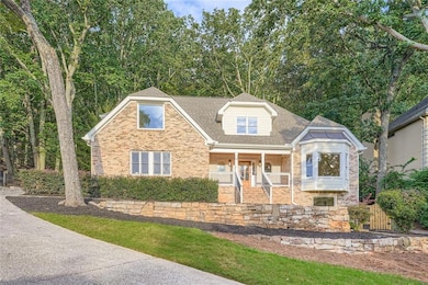 View of front facade featuring covered porch, roof with shingles, and brick siding