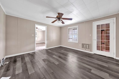 Unfurnished room with heating unit, ornamental molding, a ceiling fan, and dark wood-style flooring