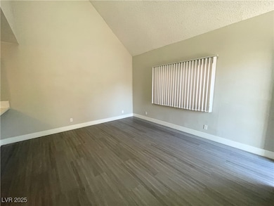 Unfurnished room featuring vaulted ceiling, dark w