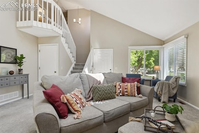 Living room with carpet, stairs, high vaulted ceiling, and baseboards
