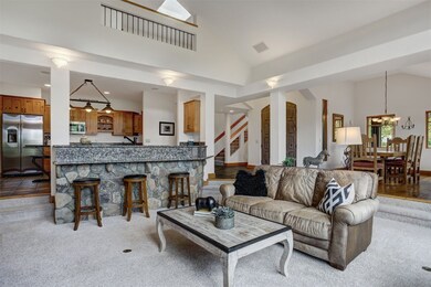 Living area featuring high vaulted ceiling, stairway, light carpet, and a chandelier