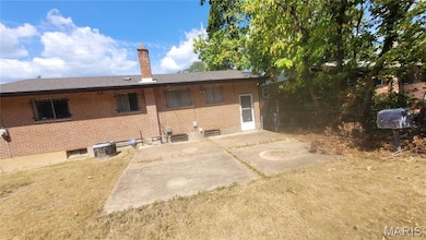 Rear view of property with a patio, a chimney, brick siding, and a lawn