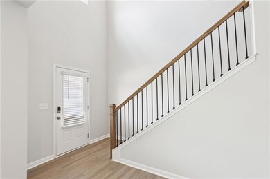 Foyer featuring a high ceiling, wood finished floors, baseboards, and stairs