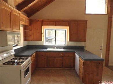 Open kitchen with wood cabinets, title counter top