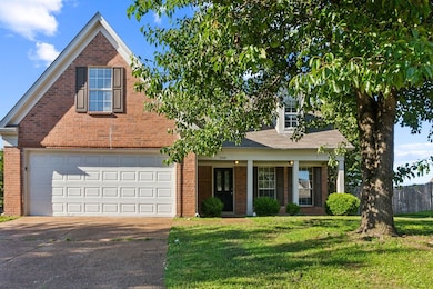 Traditional-style house with concrete driveway, brick siding, a garage, and covered porch