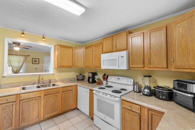 Kitchen with white appliances, light countertops, track lighting, light tile patterned floors, and ceiling fan