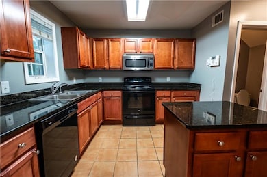 Kitchen featuring black appliances, a sink, brown cabinets, and light tile patterned flooring