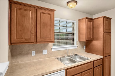 Kitchen with brown cabinets, light countertops, and backsplash