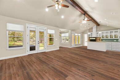 Living area open to kitchen with wall to wall windows showcasing the beautiful property and brightening the area with natural light