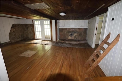 Unfurnished living room with hardwood / wood-style flooring, wood walls, a fireplace, stairs, and wooden ceiling