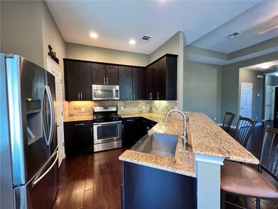 Kitchen with stainless steel appliances, light stone counters, tasteful backsplash, a peninsula, and a breakfast bar
