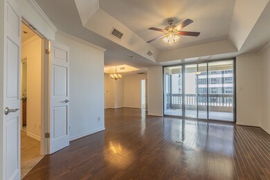 Unfurnished room featuring a chandelier, expansive windows, a raised ceiling, a ceiling fan, and dark wood-style floors