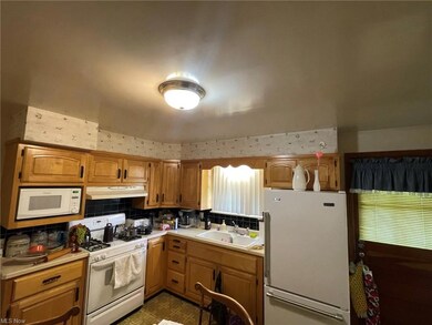 Kitchen featuring tile floors, brown cabinets, light countertops, white appliances, and backsplash