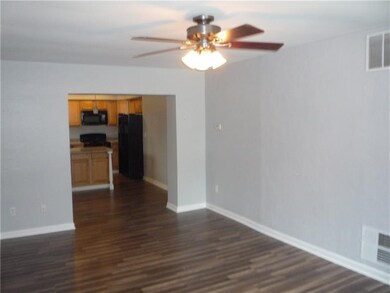 large living room has ceiling fan open to kitchen