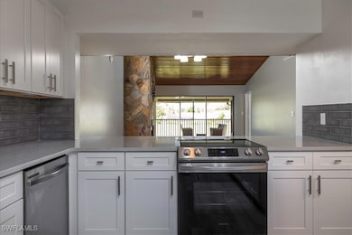 Kitchen with white cabinets, appliances with stain