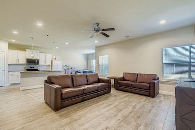 Living area with light wood finished floors, a ceiling fan, and recessed lighting