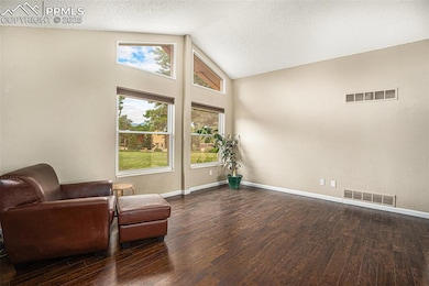 Living room featuring healthy amount of natural light, wood finished floors, a textured ceiling, and high vaulted ceiling