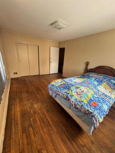 Bedroom with dark wood-style floors and a closet