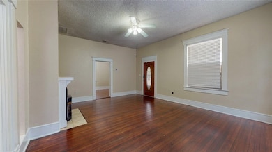 Unfurnished living room featuring a textured ceiling, wood finished floors, ceiling fan, and a fireplace with flush hearth