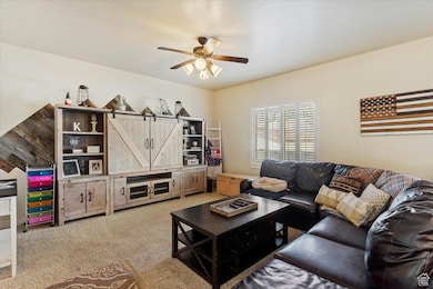 Living room featuring light carpet and a ceiling fan