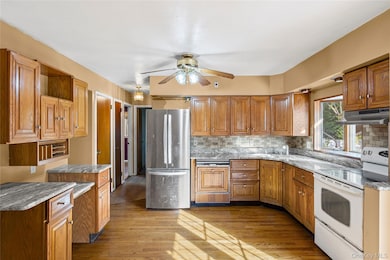 Kitchen featuring white electric range oven, brown cabinets, freestanding refrigerator, and dishwasher