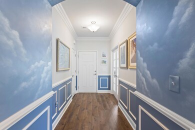 Doorway to outside with dark wood-style flooring, a wainscoted wall, crown molding, a decorative wall, and arched walkways